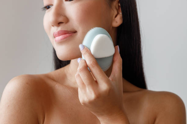 istock Asian young woman using face massager in studio 1360273527