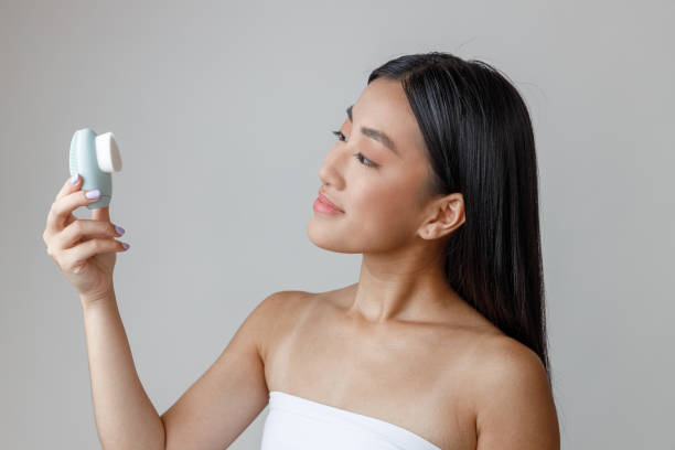 istock Asian young woman holding face massager cleansing device 1360273533