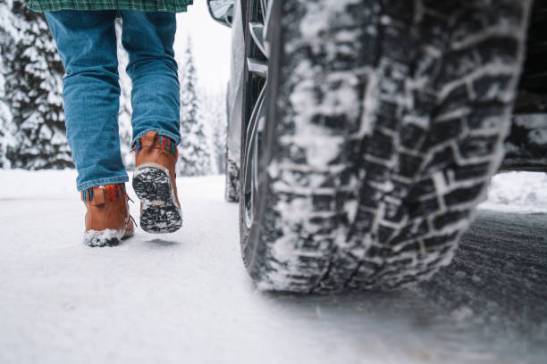 low section of woman walking on snowy road next to vehicle - sports utility vehicle 4x4 car tire imagens e fotografias de stock