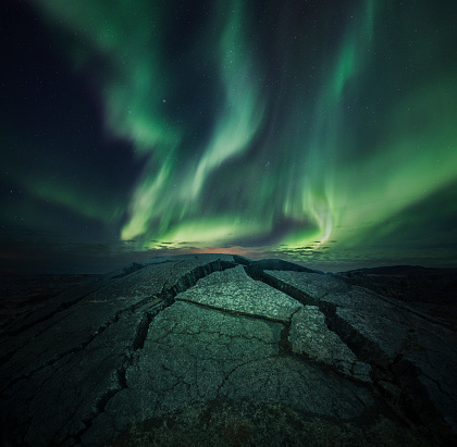 Cracks on foreground under beautiful aurora borealis, square landscape.