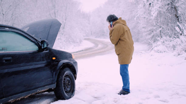 istock Man with car issues on winter road, phone calling for help. 1360275905