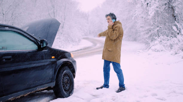 istock Man with car issues on winter road, phone calling for help. 1360275910