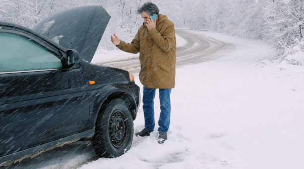istock Man with car issues on winter road, phone calling for help. 1360275912