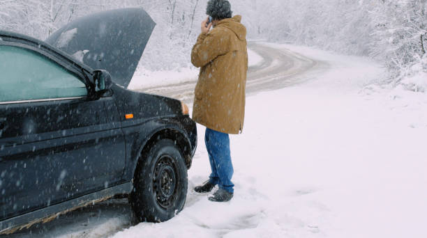 istock Man with car issues on winter road, phone calling for help. 1360275915