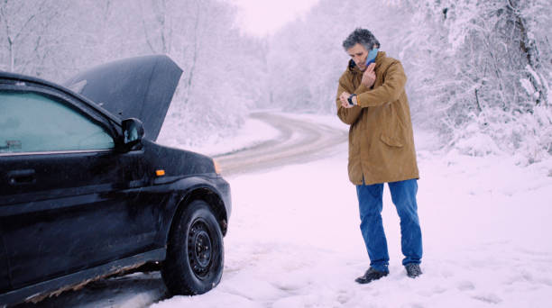 istock Man with car issues on winter road, phone calling for help. 1360275916