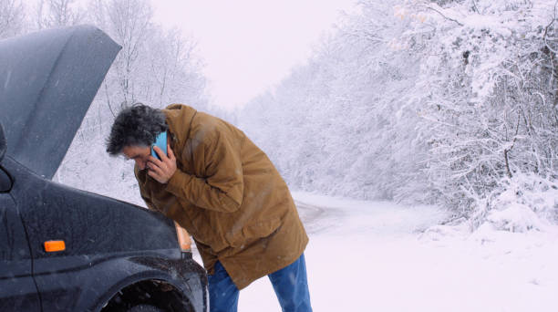 istock Man with car issues on winter road, phone calling for help. 1360275918