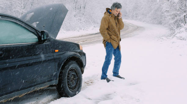 istock Man with car issues on winter road, phone calling for help. 1360275919
