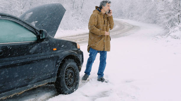 istock Man with car issues on winter road, phone calling for help. 1360275922