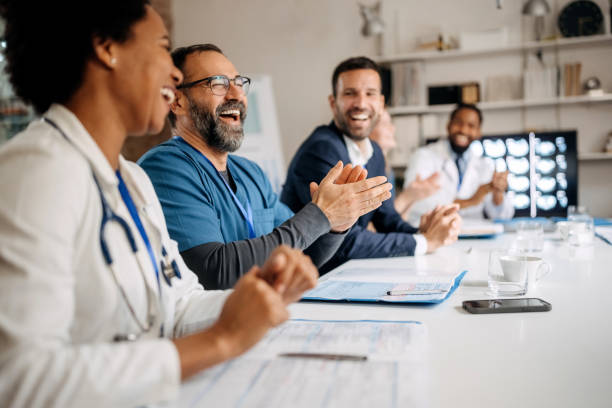 Group of doctors applauding while attending healthcare seminar stock photo