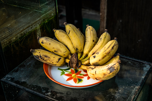 Ripe bananas on a plate as a religious offering on the street in a residential neighborhood in  Bangkok, Thailand.