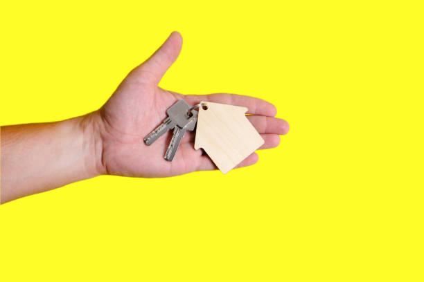 istock House keys with a keychain in hand on a yellow background. 1360299782