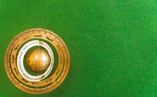 Antique Brass Sphere With A Sundial Zodiac Sign. Zodiac earth model on the green background.