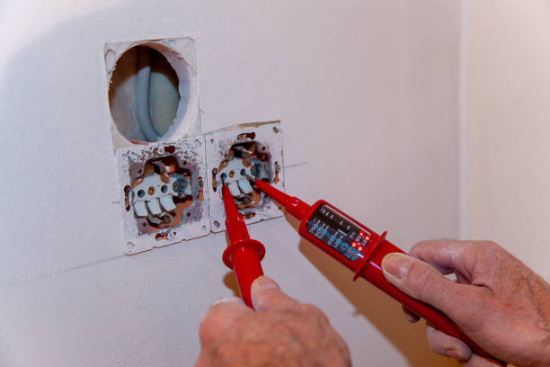 Hand of Electrician testing for electricity with a voltage tester. Electrician checking wall socket with voltage tester. stock photo