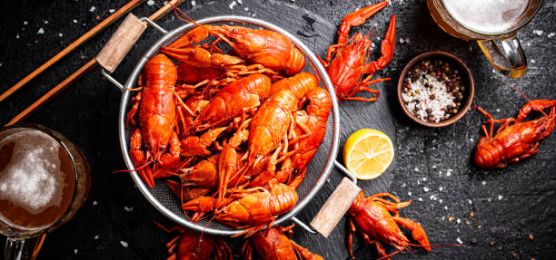 Boiled crayfish in a colander and a glass of beer. Boiled crayfish in a colander and a glass of beer. On a black background. High quality photo river crab stock pictures, royalty-free photos & images