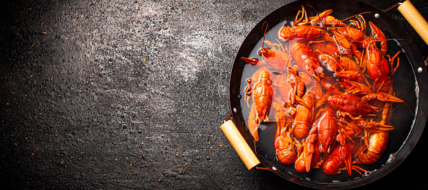 Boiled crayfish in a pot of water. On a black background. Top view. High quality photo