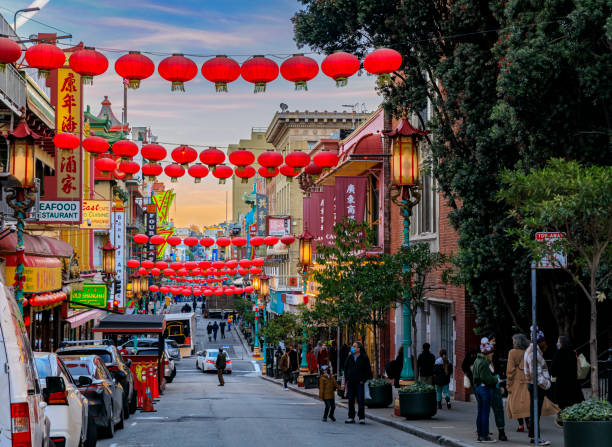 Traditional shops, lanterns and a pagoda in San Francisco Chinatown at sunset San Francisco, USA - December 18, 2021: Traditional shops, lanterns and people in the street in Chinatown near Downtown with a fiery sunset chinatown photos stock pictures, royalty-free photos & images