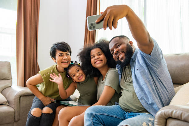 istock Happy African family using smartphone taking selfie together at home. 1360310974