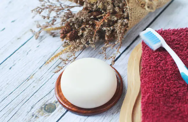 Handmade herbal glycerin soap laid on old wooden floor., Towels and toothbrushes are provided.
