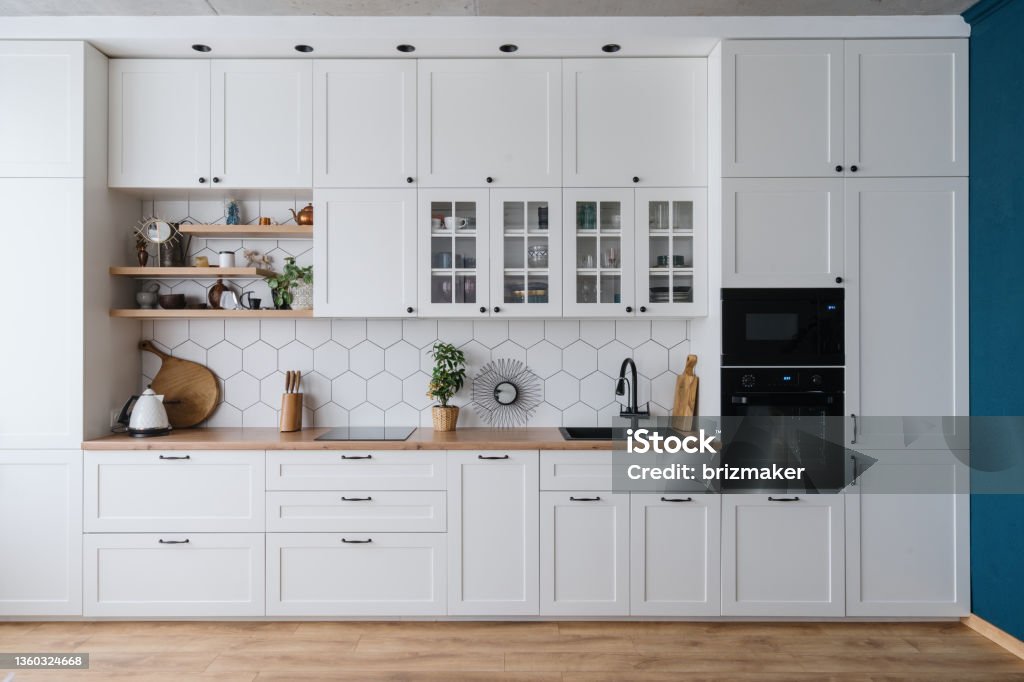 Modern home kitchen interior design in white tones Contemporary kitchen interior design with stylish furniture, appliances and decor. Bright and spacious cupboard in modern apartment. Luxury real estate for rent Kitchen Stock Photo