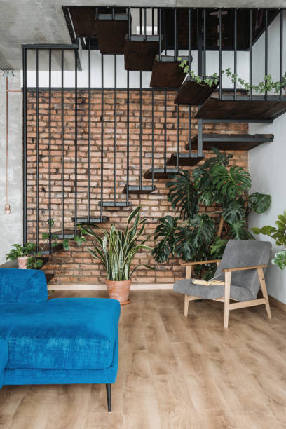 Modern furniture in loft styled duplex apartment Contemporary armchair and sofa in cozy loft styled duplex flat with stairs and plants. Home environment. Luxury apartment for sale. Modern house with stairs interior design duplex photos stock pictures, royalty-free photos & images