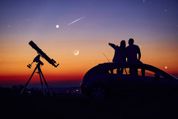 istock Couple stargazing together with a astronomical telescope. 1360325671