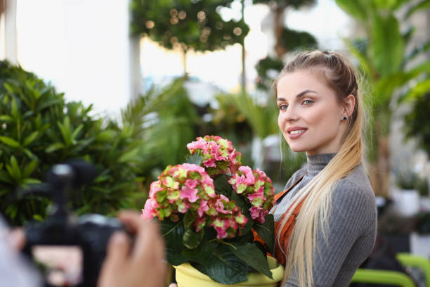 istock Beautiful blonde florist studio worker record promotion for botanical store 1360325691
