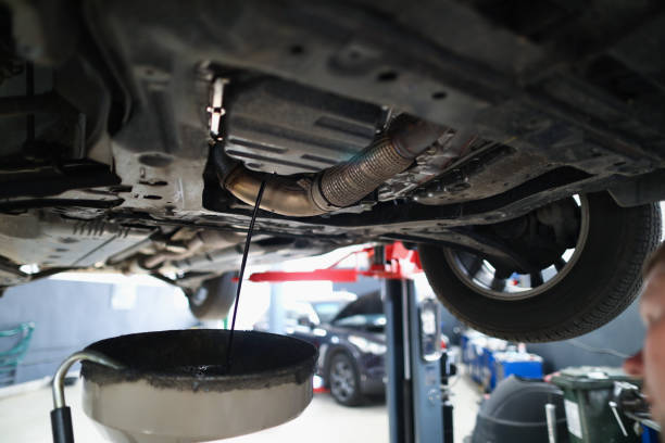 istock Automobile lifted in air dripping oil in container, worker control process 1360325736