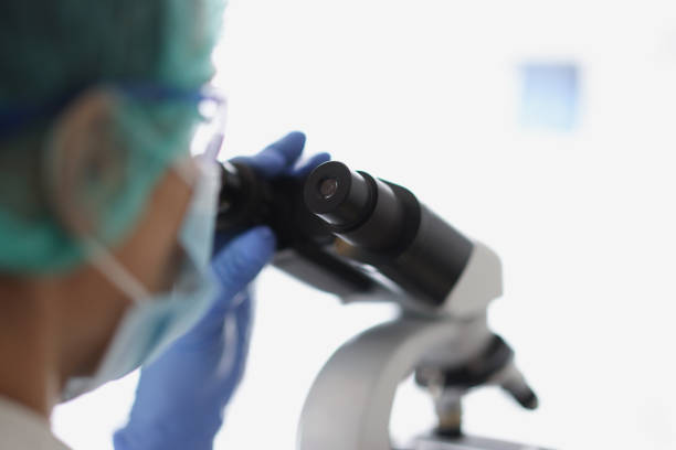 istock Woman chemist in blue protective glove look at microscope in chemistry lab 1360325741