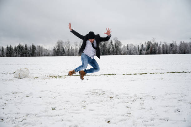 istock Joyful young man jumping in the snow 1360327876