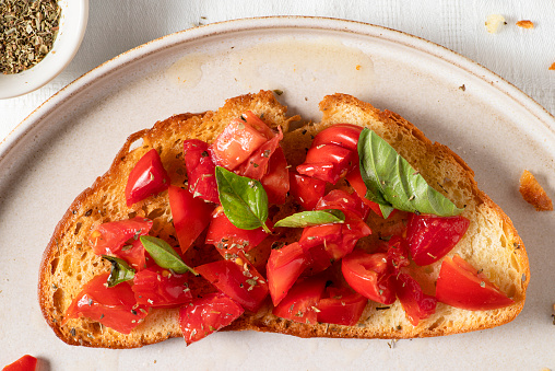 Macro of caprese bruschetta toast with cherry tomatoes and fresh garden basil. Top view