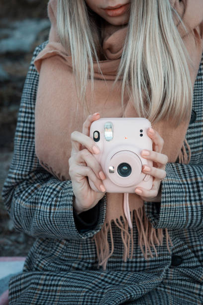istock Woman hands holding a pink instax camera 1360331222