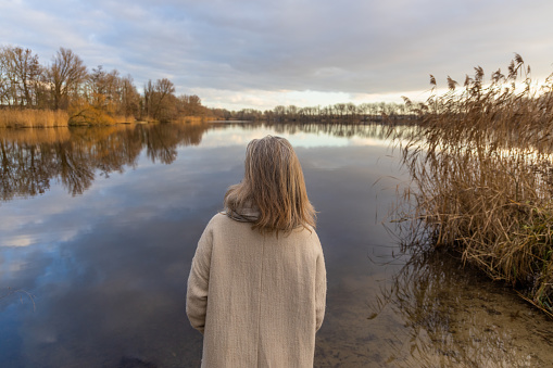 woman walking and resting and jumping at a Dutch lake at sunset in the winter