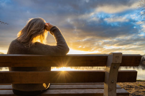 femme marchant et se reposant au lac au coucher du soleil - bench photos et images de collection