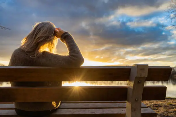 Photo of woman walking and resting at the lake at sunset