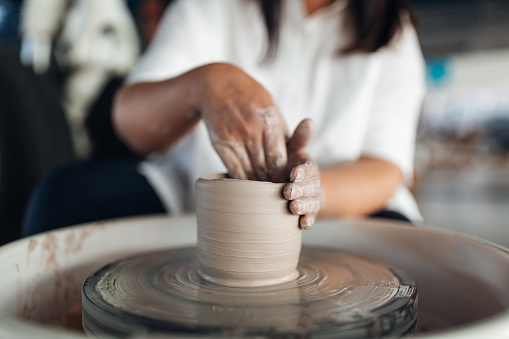 Woman sculpts an object on a potter's wheel