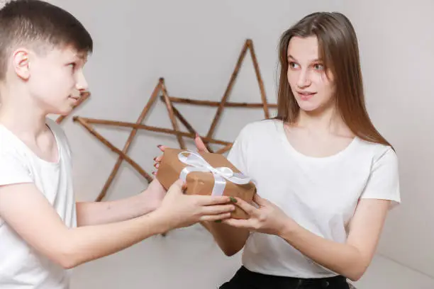 Photo of young man had giving a gift box to girl. christmas and new year concept. young boyfriend is giving surprise in box with white ribbon to his girlfriend