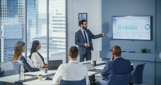 istock Office Conference Room Meeting: Digital Enterpreneur Presents e-Commerce Investment Strategy for Group of Investors. Wall TV Showing Big Data Analysis, Infographics, Stock Market Information, Trends 1360337391