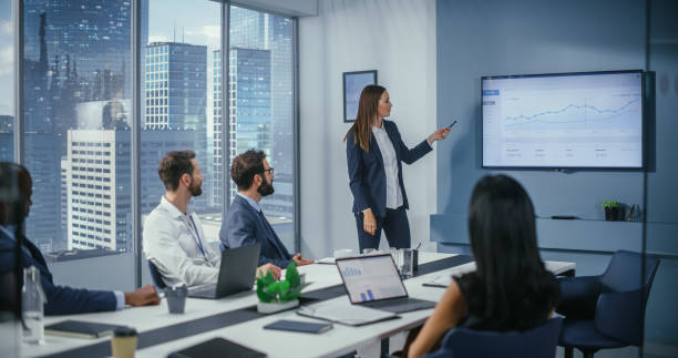 istock Diverse Office Conference Room Meeting: Successful Female Executive Director Presents e-Commerce Fintech Growth Statistics to a Group of Investors. Wall TV with Big Data Analysis, Infographics 1360337422