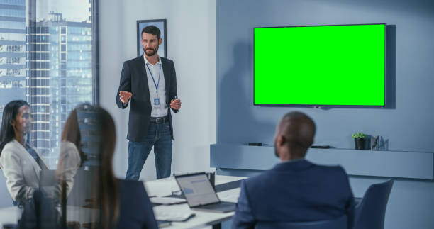 büro konferenzraum meeting präsentation: handsome businessman talks, verwendet green screen chroma key wand-tv. erfolgreiche präsentation eines e-commerce-produkts vor einer gruppe multiethnischer investoren - multi ethnic group business meeting 20s 30s stock-fotos und bilder