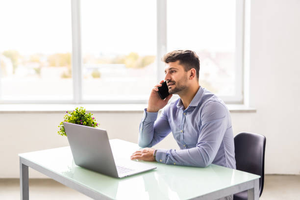 istock Smiling businessman talking on phone in office 1360339330
