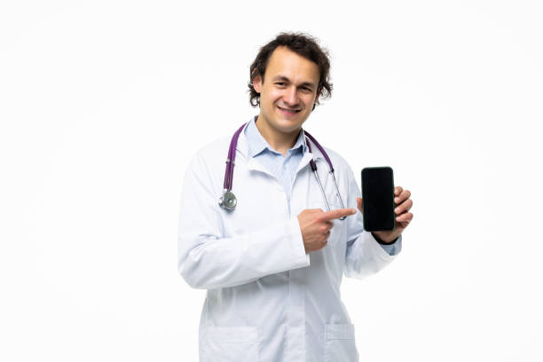 istock Doctor presenting smart phone and pointing blank black screen with copyspace for ads isolated on white background, 1360341898