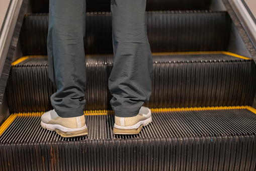 Standing on the steps of the escalator with one pair of feet