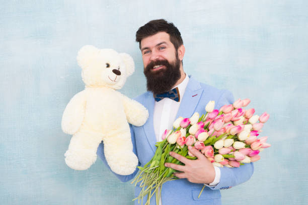 womens day. Formal mature businessman bride groom at wedding party. love date with flowers. Happy Birthday. spring bouquet. 8 of march. bearded man in bow tie with tulip flowers. Young and carefree womens day. Formal mature businessman bride groom at wedding party. love date with flowers. Happy Birthday. spring bouquet. 8 of march. bearded man in bow tie with tulip flowers. Young and carefree. man with teddy bear stock pictures, royalty-free photos & images