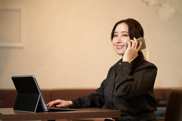 The owner of a restaurant who makes a phone call while looking at a computer
