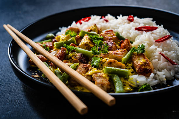 istock Roast chicken meat, white rice and vegetables on wooden table 1360346917