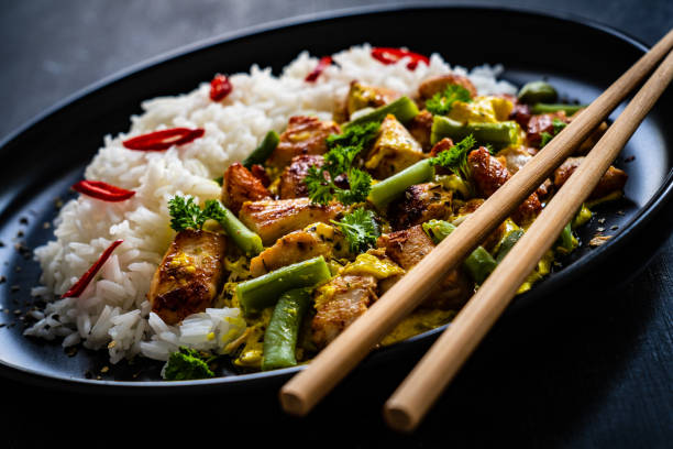 istock Roast chicken meat, white rice and vegetables on wooden table 1360346978