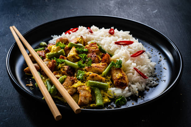 istock Roast chicken meat, white rice and vegetables on wooden table 1360347009
