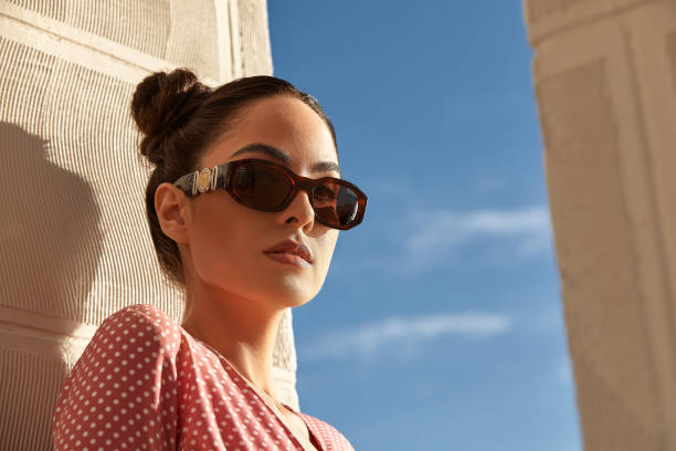 a portrait of a beautiful woman in sunglasses against blue sky stock photo
