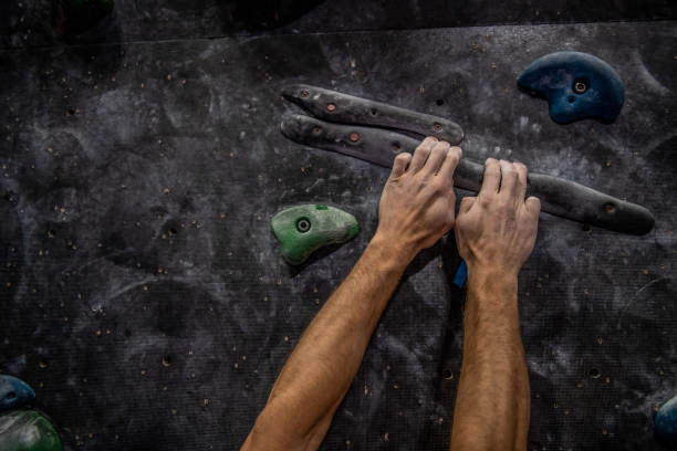 Athletic man bouldering at an indoor climbing center. Professional climber climbing wall upside down at an indoor climbing gym.
