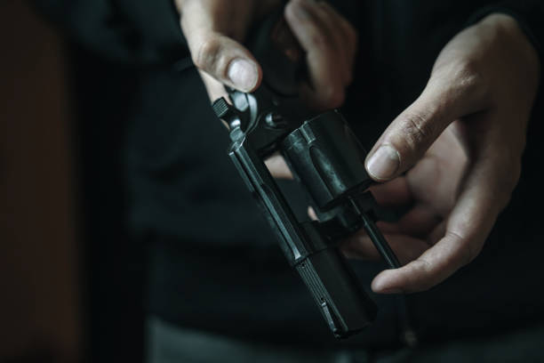 istock Men's hands check for bullets in revolver barrel. 1360350424